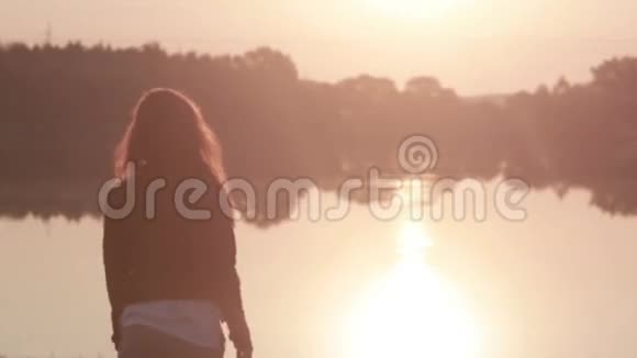 小女孩慢慢地举起双手欣赏河上的日出然后转身看着镜头视频的预览图