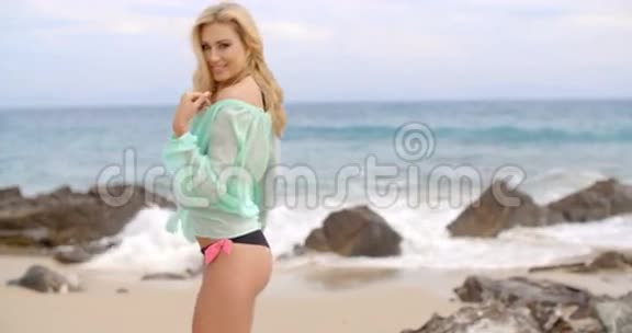 比基尼的金发女人在落基海滩的封面上视频的预览图