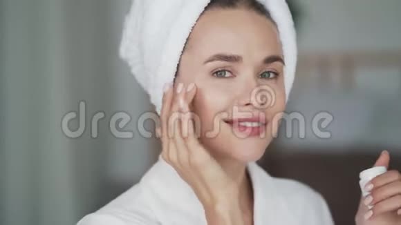 头上有毛巾的女人脸上涂了润肤霜闭上嘴视频的预览图