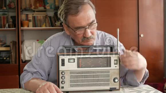 有胡子的老人打开老式收音机听音乐拔出天线打开按钮视频的预览图