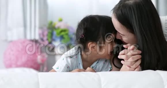 年轻的亚洲母亲和孩子亲吻拥抱一起躺在床上视频的预览图