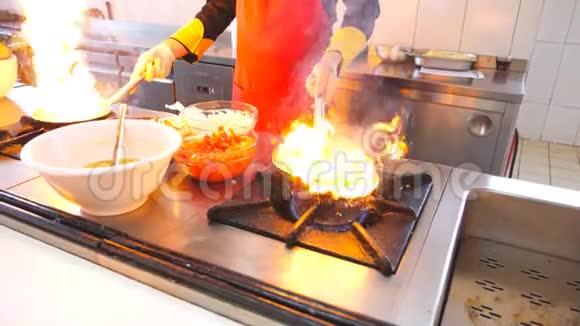 专业厨师手拿两个平底锅在现代餐厅厨房烹饪弗拉姆贝式菜肴男性厨师视频的预览图