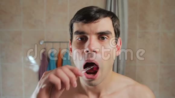 年轻迷人的男人刷牙照镜子他用牙刷刷牙对儿童的照料视频的预览图