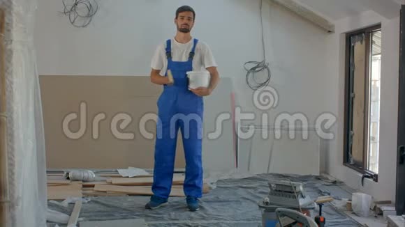 一个年轻的建筑工人对着镜头说话一座正在建造的房子在后台视频的预览图