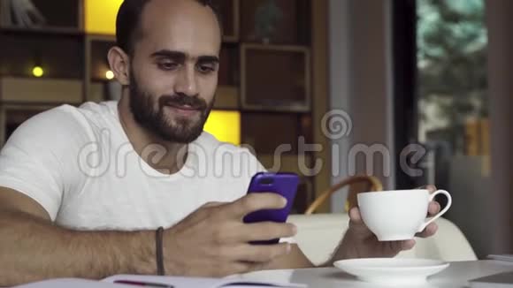 男人在智能手机上使用应用程序喝咖啡在手机上发短信视频的预览图