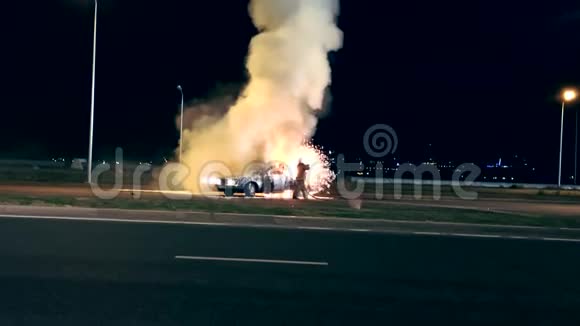 一名消防队员在车祸现场用泡沫把燃烧着的汽车浸湿视频的预览图