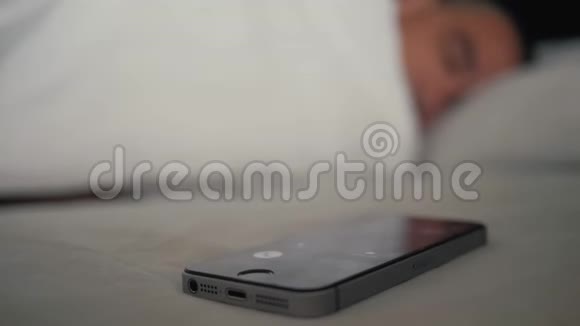 年轻人睡在床上手机显示器上有闹钟现代技术视频的预览图