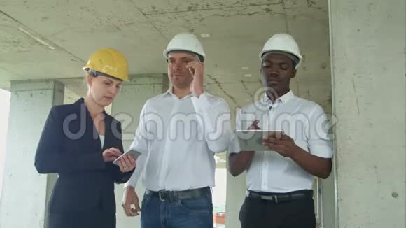 建筑工地执行小组用平板电脑智能手机正式着装人员阅读建筑平板电脑视频的预览图