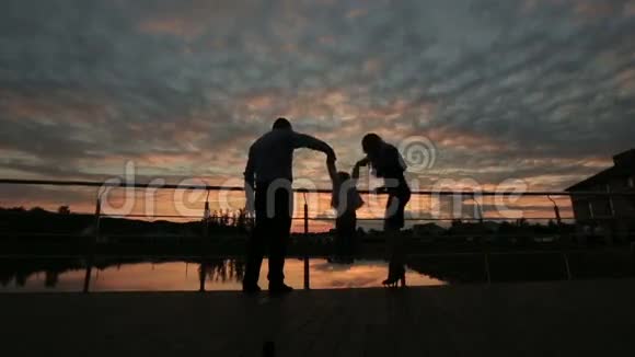 日落时分幸福的家庭在一起散步的剪影视频的预览图