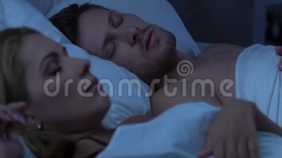 一对睡在床上的夫妇不高兴的妻子被丈夫的响亮的呼噜声吵醒了视频的预览图