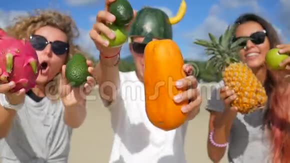 快乐美丽的年轻素食主义者朋友们在海滩上玩着无聊的游戏和异国情调的泰国水果跳舞泰国范甘视频的预览图