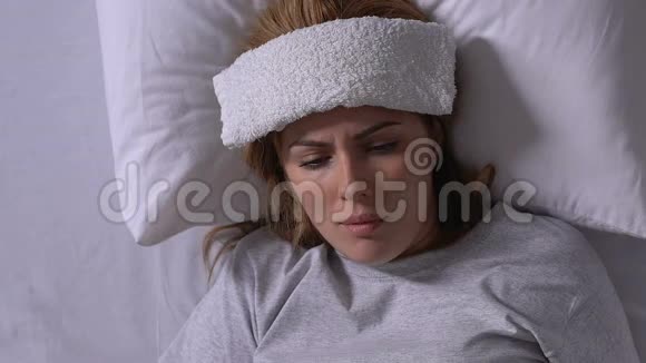 带毛巾额头的患病女士在床上咳嗽免疫系统低下感染流感病毒视频的预览图