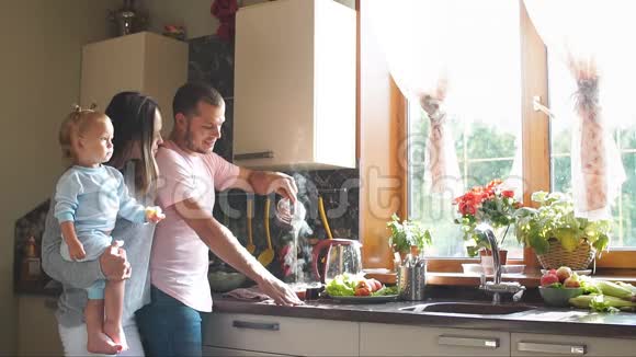 快乐的年轻家庭在厨房准备早餐慢动作视频的预览图