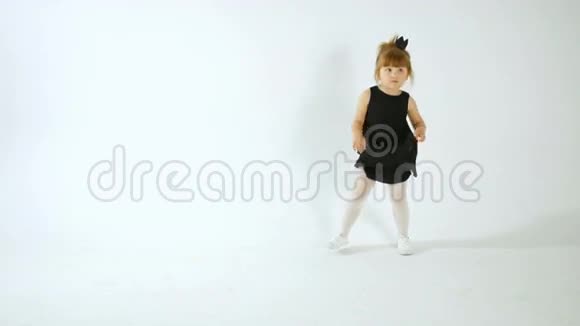 可爱的小女孩穿着黑色的裙子跳舞玩得很开心被隔离在白色的身上视频的预览图