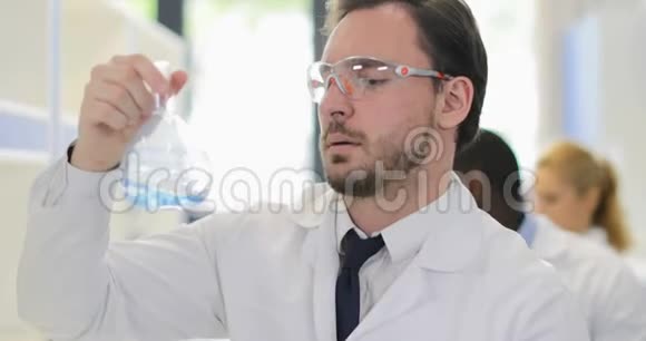 在化学实验室工作时男性科学家分析面粉中液体的气味戴上白色外套和防护眼镜视频的预览图