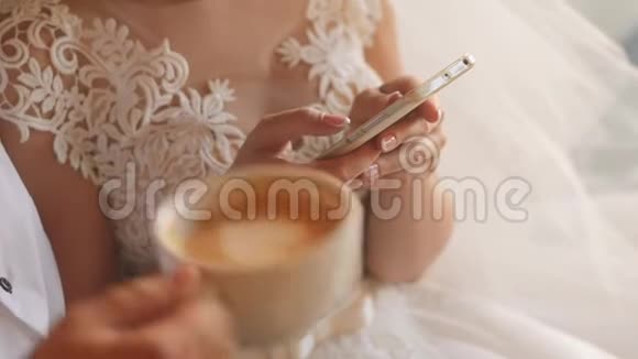 新娘穿着婚纱手里拿着智能手机新郎在喝卡布奇诺视频的预览图