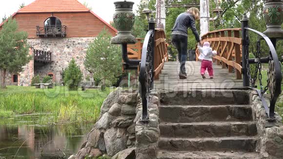 快乐的妈妈在公园里教宝宝走在河上的独木桥上4K视频的预览图