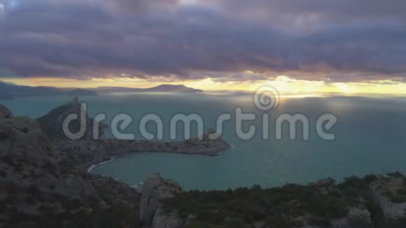 无人机在日出时快速向后飞过站在岩石上的登山者鸟瞰图视频的预览图