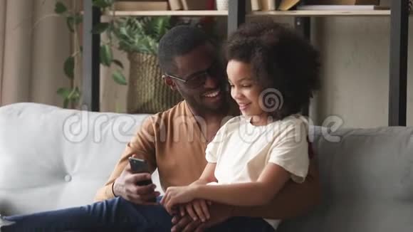 非洲父亲和女儿在使用移动音乐应用程序时玩得开心视频的预览图