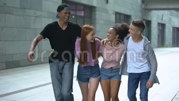 拥抱着一群多民族的青少年在街上散步笑着玩着视频的预览图