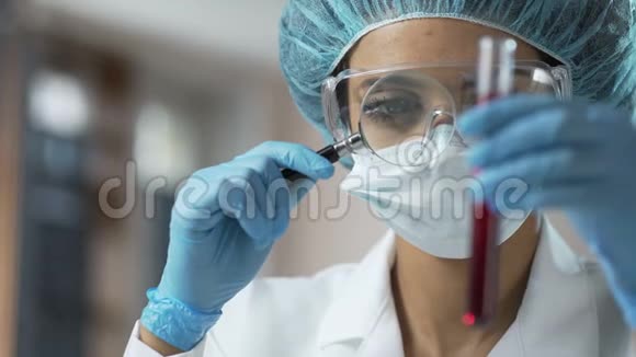 女医务工作者通过放大镜观察血液检测分析视频的预览图