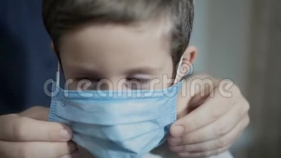 一个男人把医疗面具戴在男孩身上视频的预览图