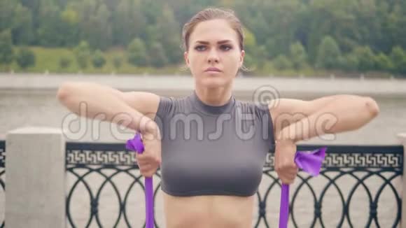运动女子在夏季公园用健身拓展器做健身运动视频的预览图