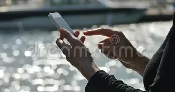 一个女孩在海边使用智能手机游艇和在港口航行视频的预览图