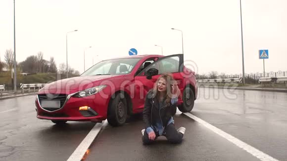 少女坐在潮湿的柏油路上撞坏的汽车附近出事了视频的预览图