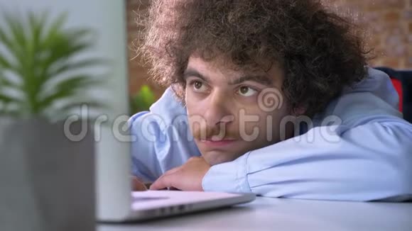 无聊的书呆子老板卷发和胡子躺在桌子上用笔记本电脑工作现代办公背景视频的预览图