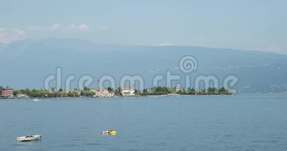 在加尔达湖的托斯科拉诺马德诺的背景下经过的一艘船视频的预览图