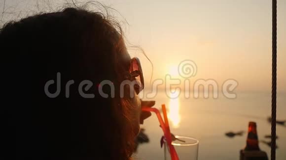 年轻的美女戴着太阳镜享受着热带龙舌兰日出的酒精鸡尾酒在那里装饰着鲜花视频的预览图