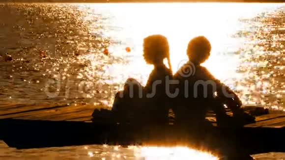 日落时分坐在桥上的小男孩和小女孩视频的预览图