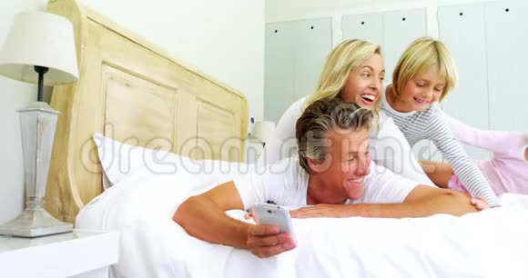 幸福的一家人在4k床房用手机自拍视频的预览图