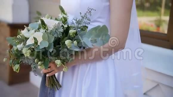 新娘穿着蕾丝连衣裙手持美丽的白色和绿色的婚礼花束特写视频的预览图