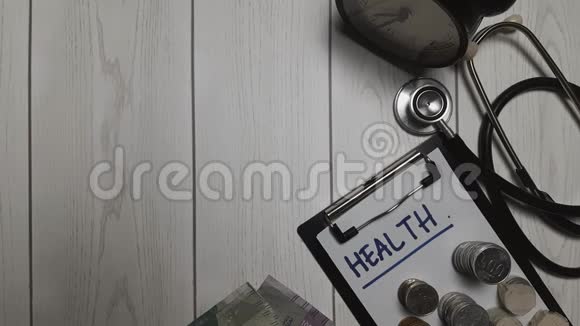 一位医生正在计算印尼卢比的每日收入健康写在剪贴板和听诊器上金融或医学概念4视频的预览图