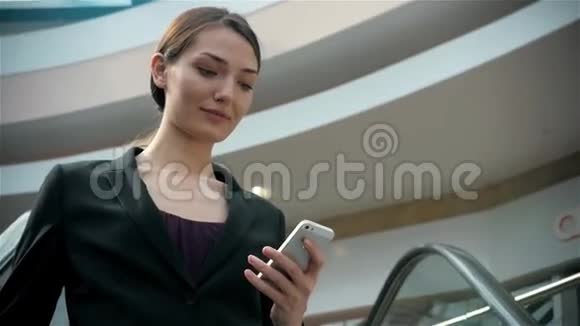 快乐的年轻女人在购物中心使用智能手机机场候机楼有智能手机的女商人视频的预览图