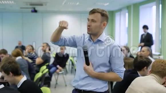 职业教练穿着蓝色衬衫对着麦克风讲话在车间为未来的高级管理人员做手势视频的预览图