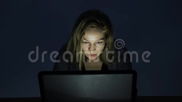 严肃的年轻女人在黑暗的房间里用电脑看着显示器开始生气视频的预览图