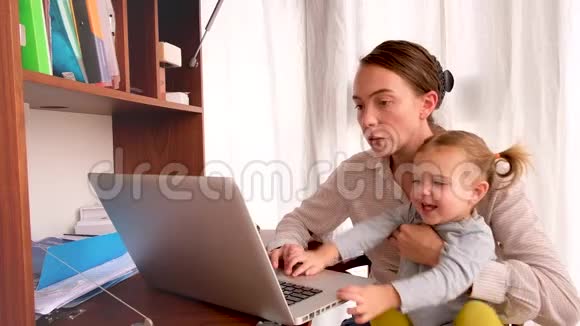 带着孩子在餐桌旁工作的母亲视频的预览图