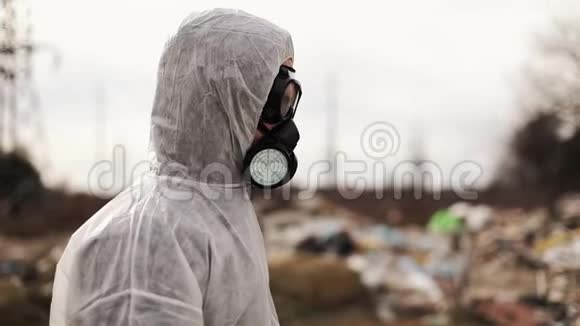 穿戴防护服装和防毒面具的病毒学家在垃圾填埋场附近行走污染生态灾害视频的预览图