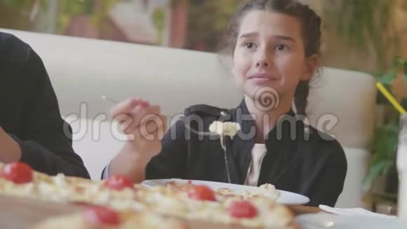 少女在咖啡厅慢动作视频里吃披萨孩子们吃比萨饼吃美味的比萨饼人们的生活方式视频的预览图