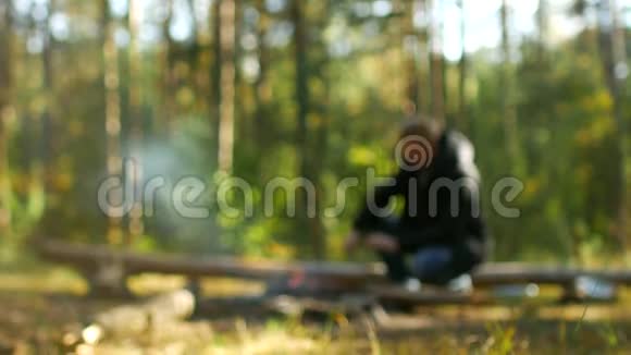 一个人在大自然的树林里生火户外娱乐模糊背景野营视频的预览图