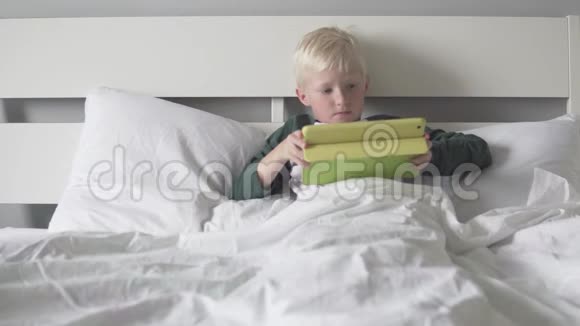 金发男孩躺在床上拿着药片视频的预览图