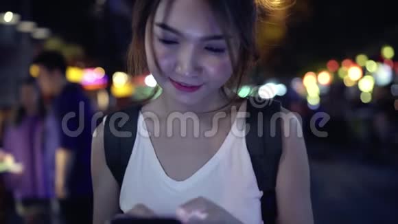 慢动作亚洲女性旅游背包客微笑和使用智能手机独自旅行户外城市街道视频的预览图