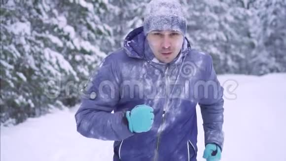 冻僵的男运动员穿过雪林冬季活动视频的预览图
