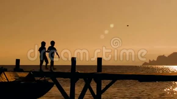 日落时分两个孩子在桥上奔跑视频的预览图
