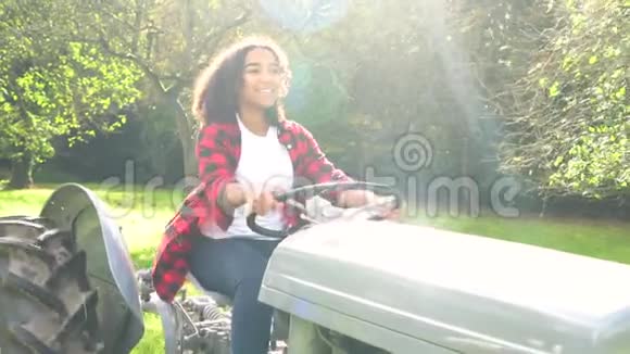 穿着灰色拖拉机穿过阳光明媚的苹果园的少女视频的预览图