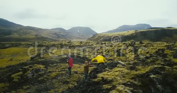在冰岛熔岩上徒步旅行的一群游客的鸟瞰图女摄影师拿着相机等着朋友视频的预览图