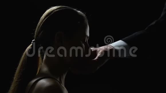 男人在黑色背景下抬起顺从的女人的头性奴役视频的预览图